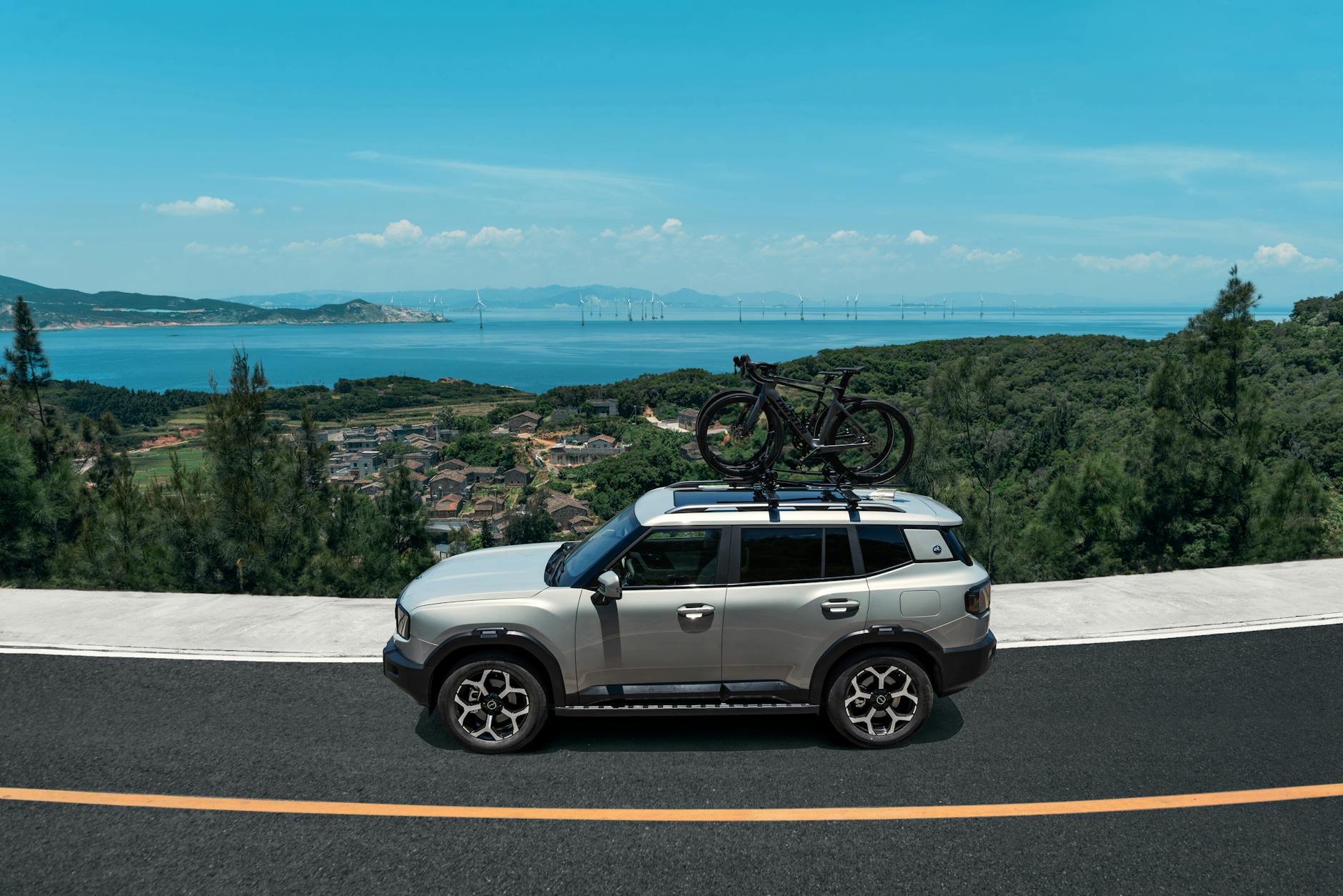 Srebrny SUV Renault jedzie nadmorską drogą z rowerami na dachu