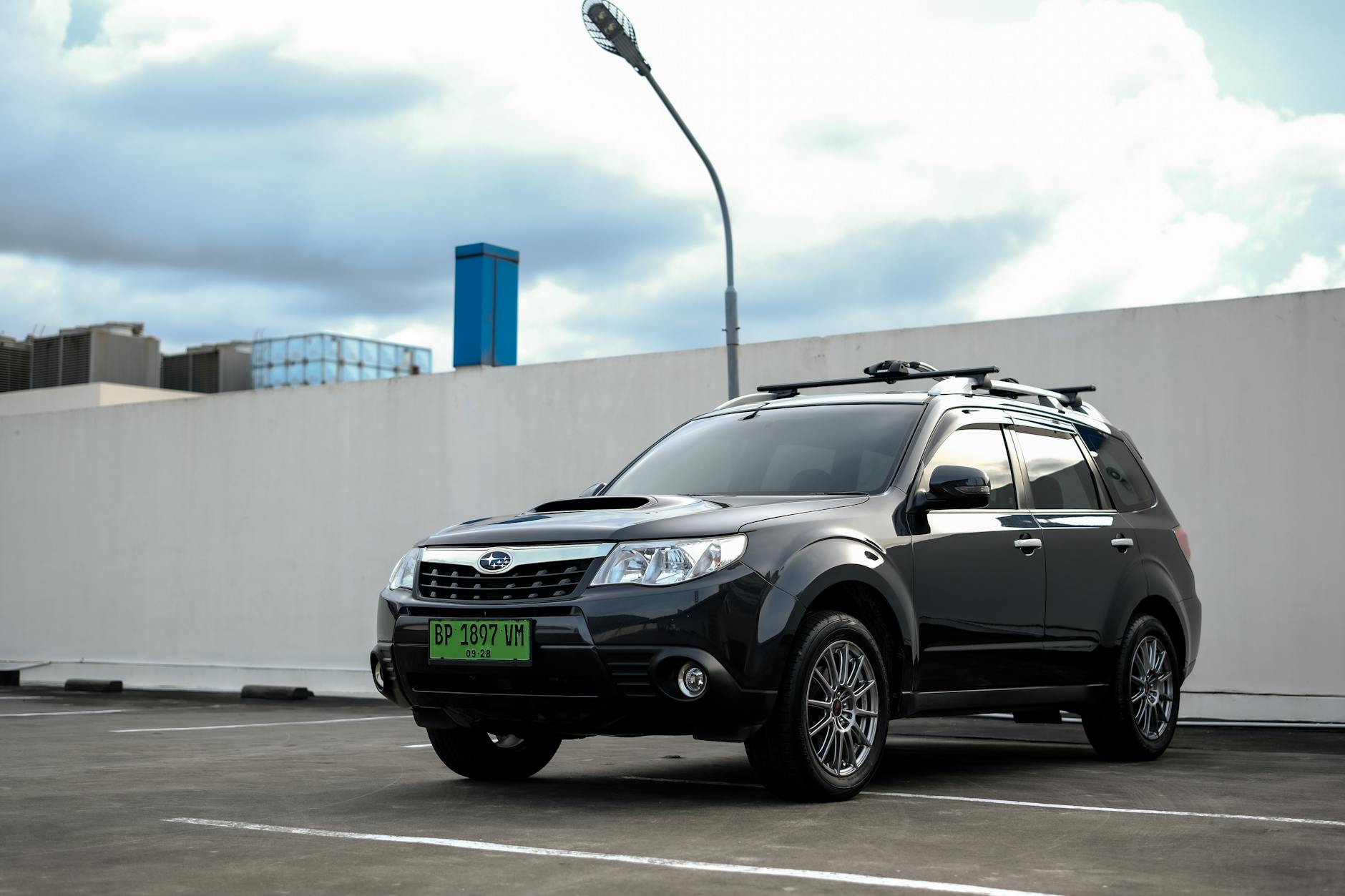 Czarny SUV Subaru Forester na miejskim parkingu pod zachmurzonym niebem