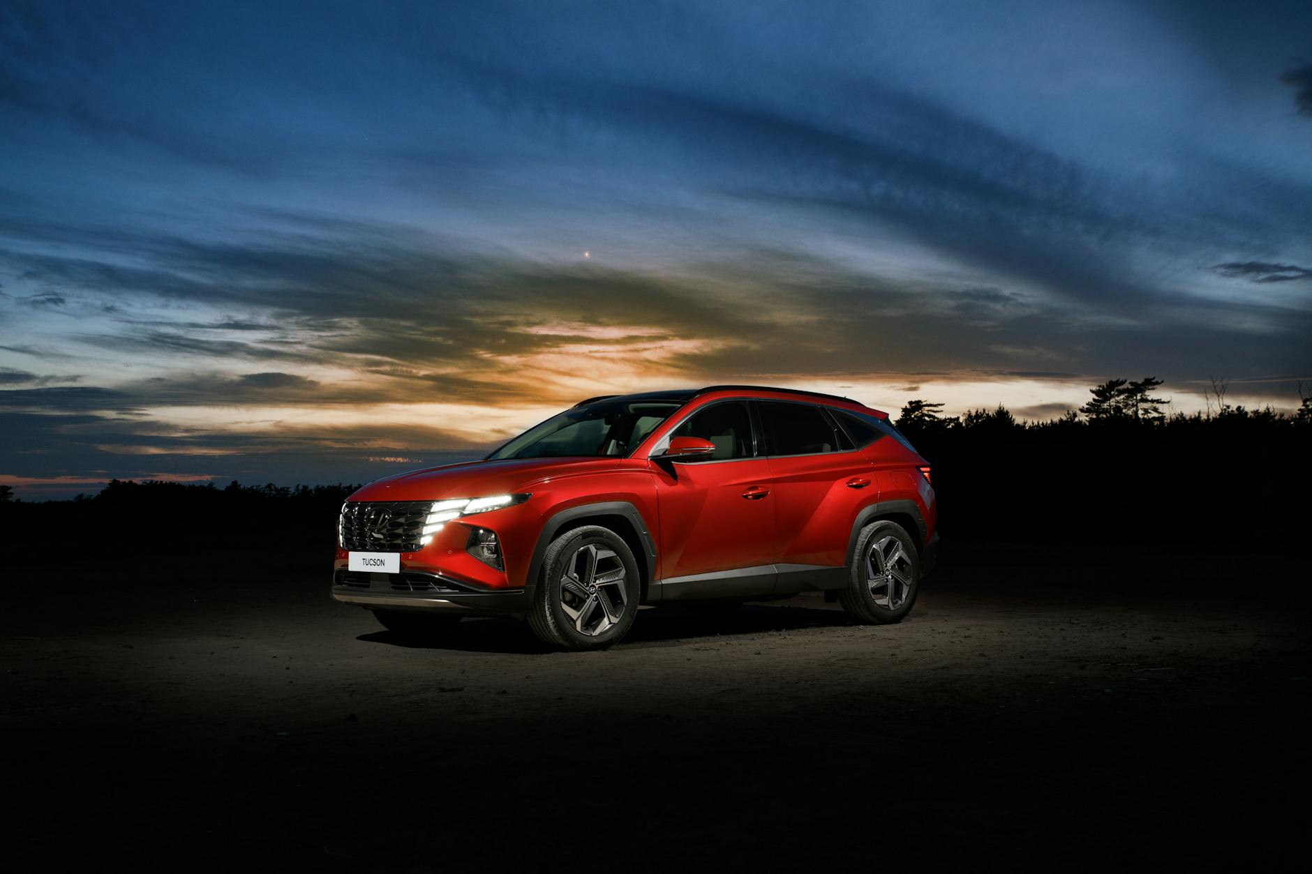 Czerwony SUV Hyundai Tucson zaparkowany na szosie o zachodzie słońca