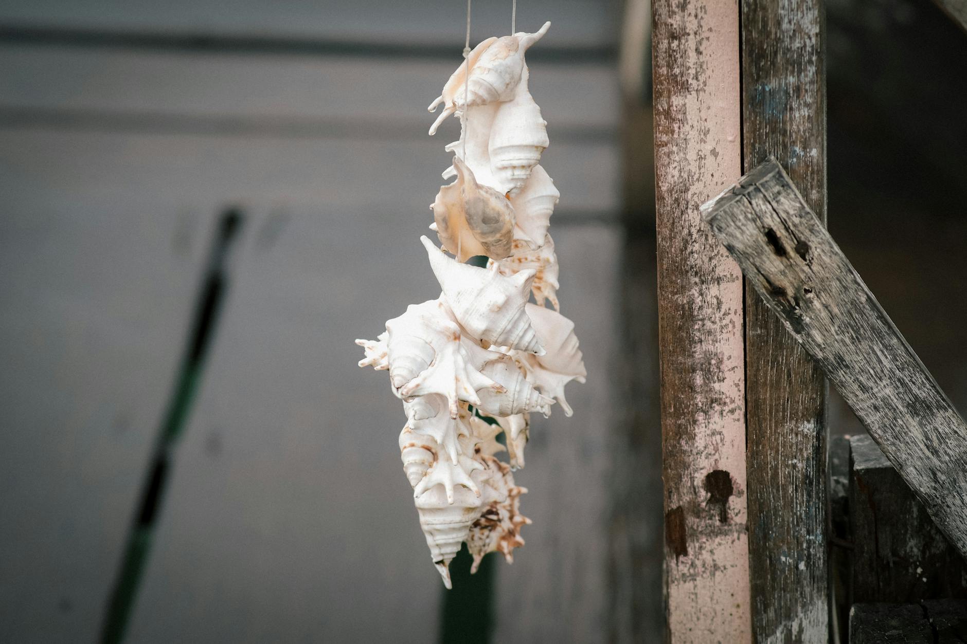 Wisząca biała dekoracja z muszelek na rustykicznym drewnianym słupku