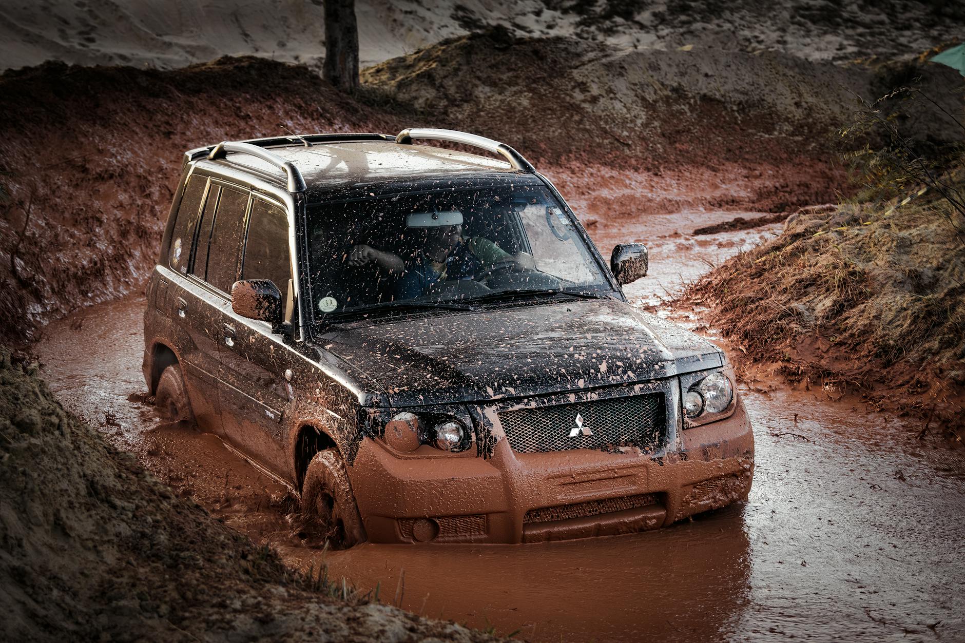 Mitsubishi SUV jadący po błotnistym, terenowym szlaku