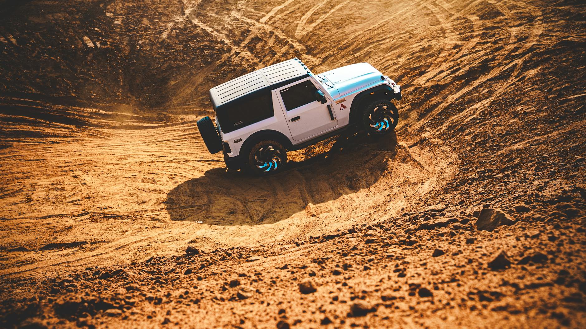 SUV jedzie dynamicznie po piaszczystych wydmach w terenie