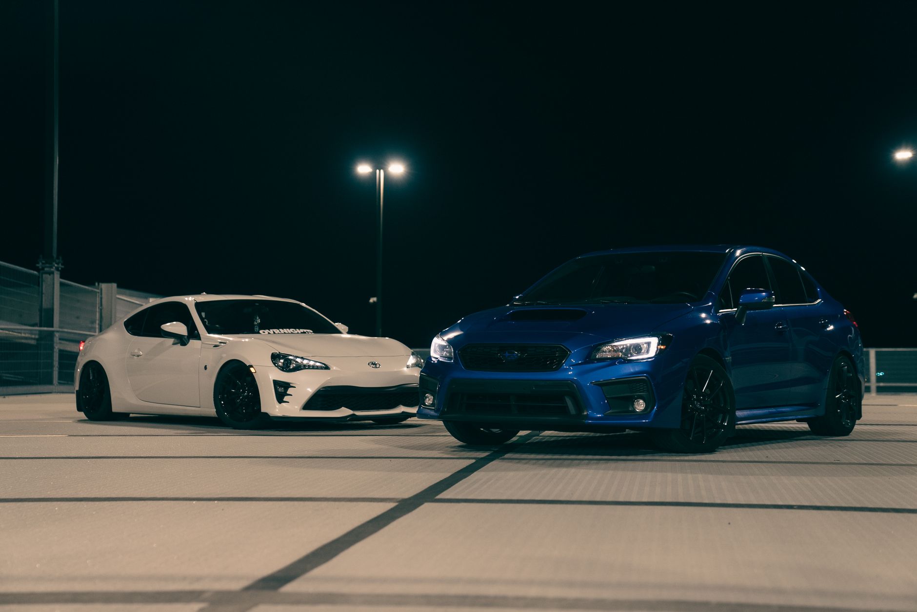 Biały i niebieski sportowy Hyundai zaparkowane nocą na dachu parkingu Biały i niebieski sportowy Hyundai zaparkowane nocą na dachu parkingu