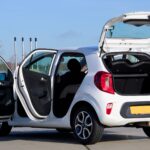 Biała Skoda Fabia z otwartymi drzwiami i bagażnikiem w miejskiej scenerii
