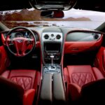 Czerwone, luksusowe wnętrze Rolls‑Royce’a z widokiem na góry za szybą