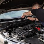 Mechanik naprawia silnik samochodu na zewnątrz w świetle dnia