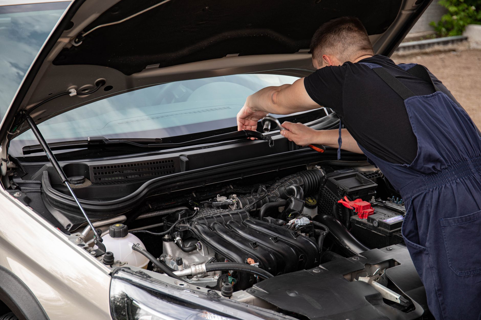 Mechanik naprawia silnik samochodu na zewnątrz w świetle dnia
